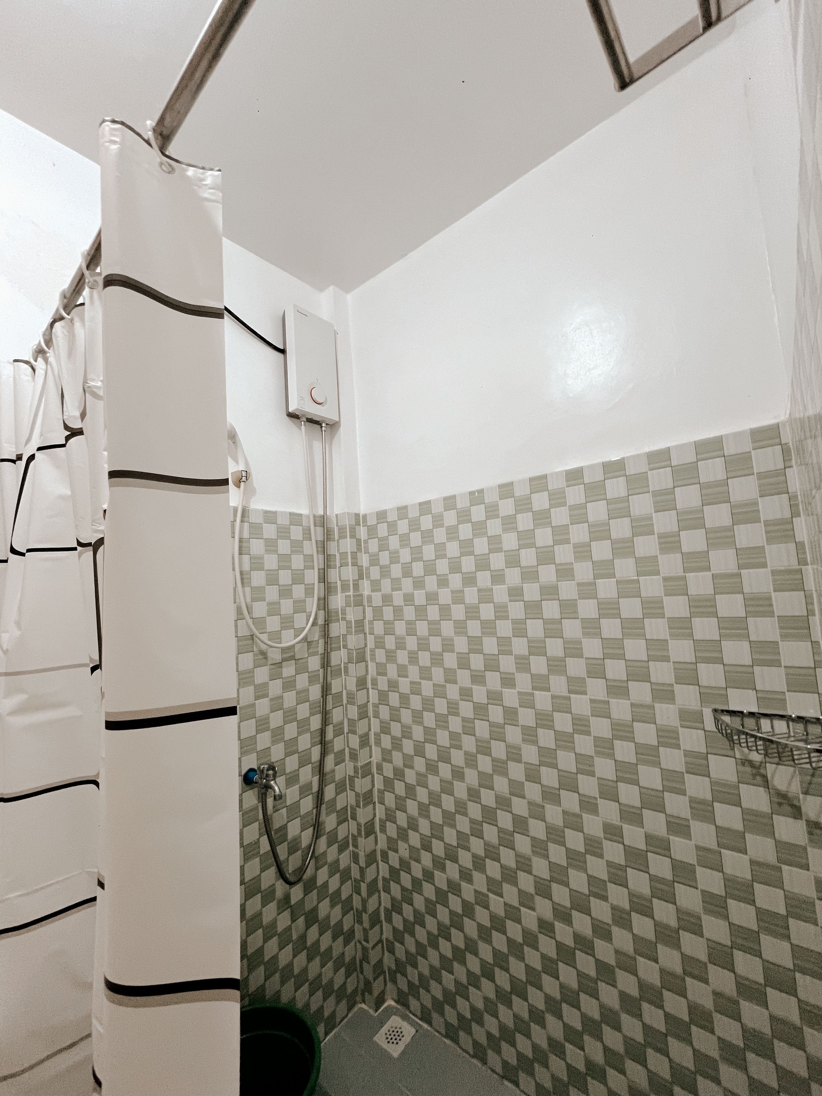 A bathroom with a shower, a toilet, and a tiled wall.