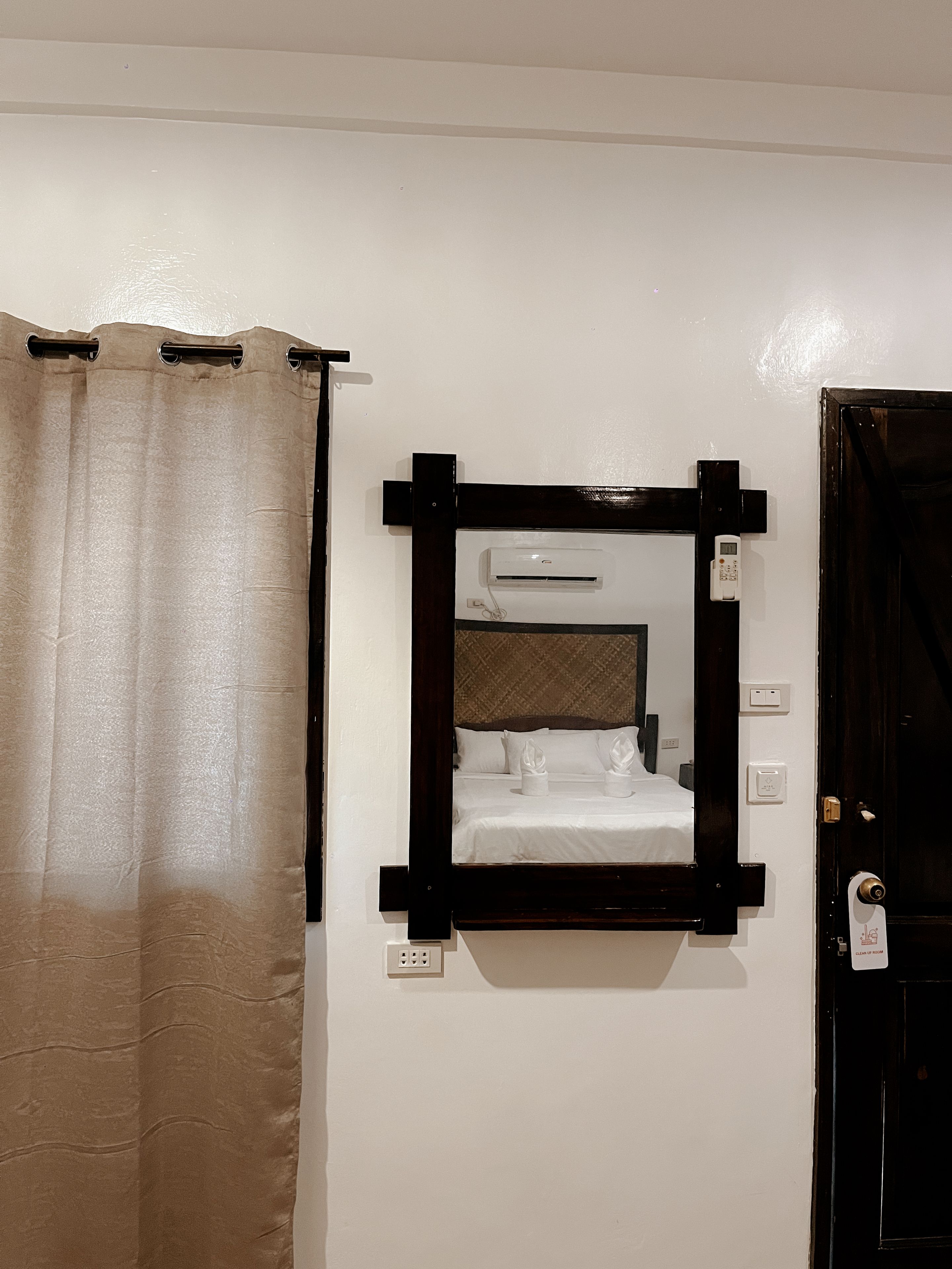 Una camera d'albergo con un letto, un condizionatore, una porta e una tenda.