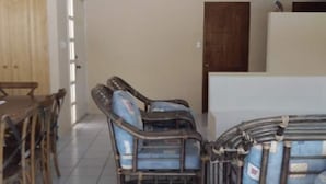 Una habitación con una puerta de madera, una mesa de comedor con sillas y un sillón azul con cojín y estructura metálica.