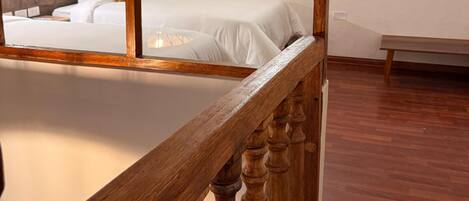 Un dormitorio con techo de madera y cama con ropa de cama blanca.