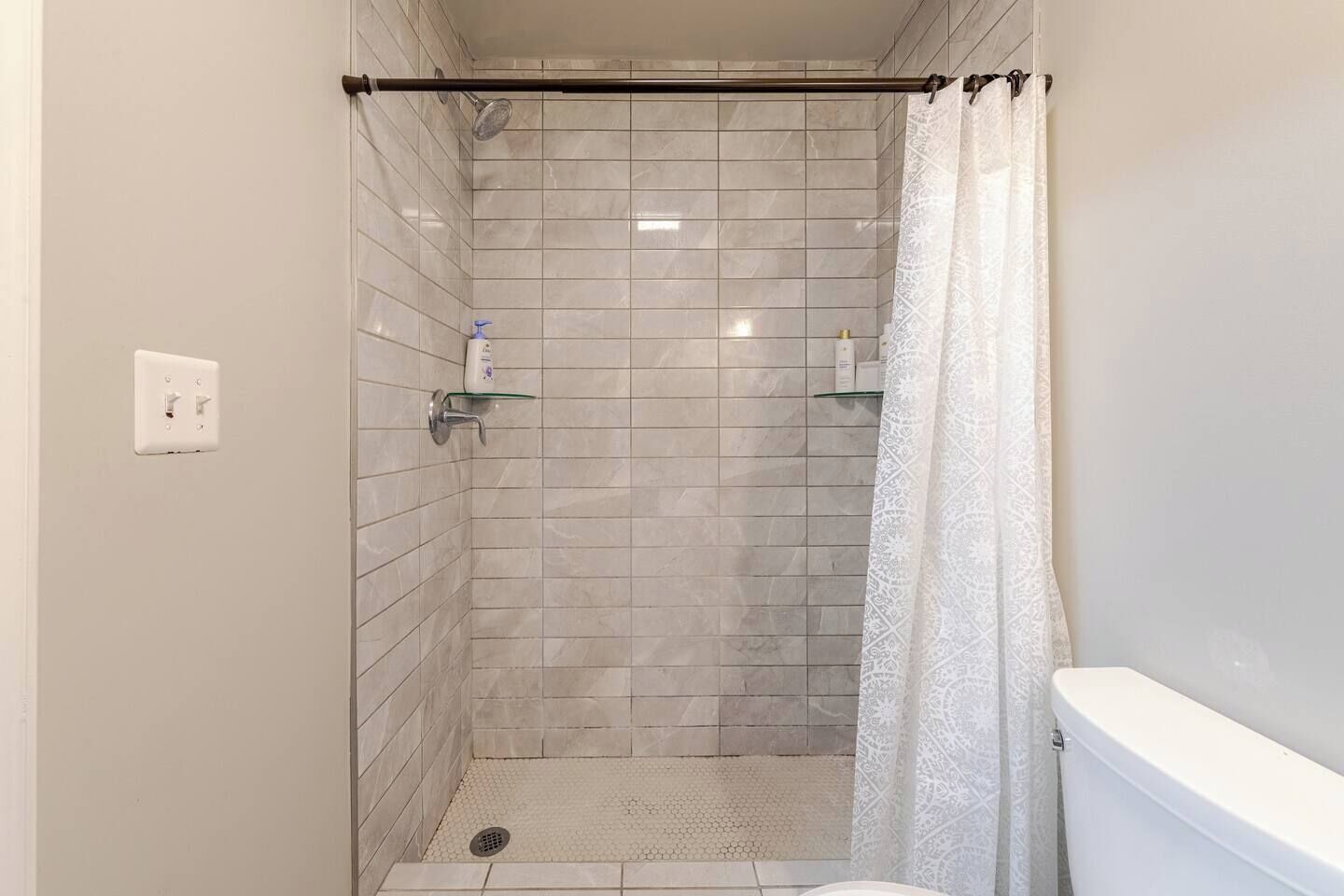 Basement full bath — walk-in tile shower with stocked toiletries