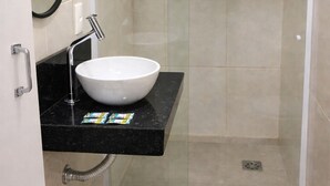 A bathroom with a white sink, a black countertop, a glass shower enclosure, and a brown doormat. - Cozy Studio in the Heart of Rio (Near Lapa) (Rio de Janeiro)