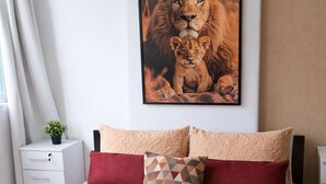 A neatly made bed with a red and beige bedspread, a geometric patterned pillow, and a stack of folded towels. - Cozy Studio in the Heart of Rio (Near Lapa) (Rio de Janeiro)