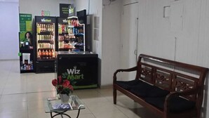 A lobby with a reception desk, a WizzMart kiosk, a wooden bench, and a tiled floor. - Cozy Studio in the Heart of Rio (Near Lapa) (Rio de Janeiro)