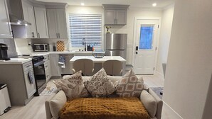 A modern living room with a sofa, patterned rug, and a kitchen in the background. - Cozy luxury-1 bedroom guest suite in Concord -walk to BART-close to Mt Diablo. (Concord)