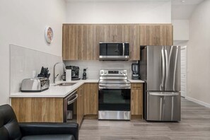 Een moderne keuken met houten kastjes, roestvrijstalen apparatuur, een broodrooster en een koffiezetapparaat.