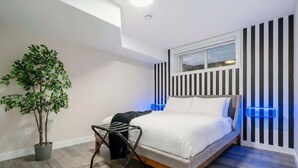 A modern bedroom with a bed, a potted plant, a chair, and a window. - Arcade, Great Coffee, 80 min Banff, Brand New (Calgary)