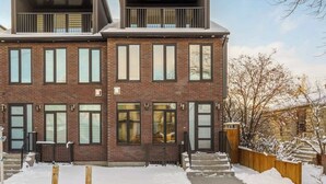 A modern two-story brick building with large windows and a balcony. - Trendy Bridgeland | Fireplace | King Beds | AC (Calgary)