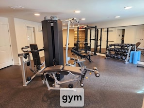 A gym with exercise equipment, weight racks, and a sign labeled 'gym'. - Enchanted Rooftop Escape | Beautiful Sunsets (Surrey)