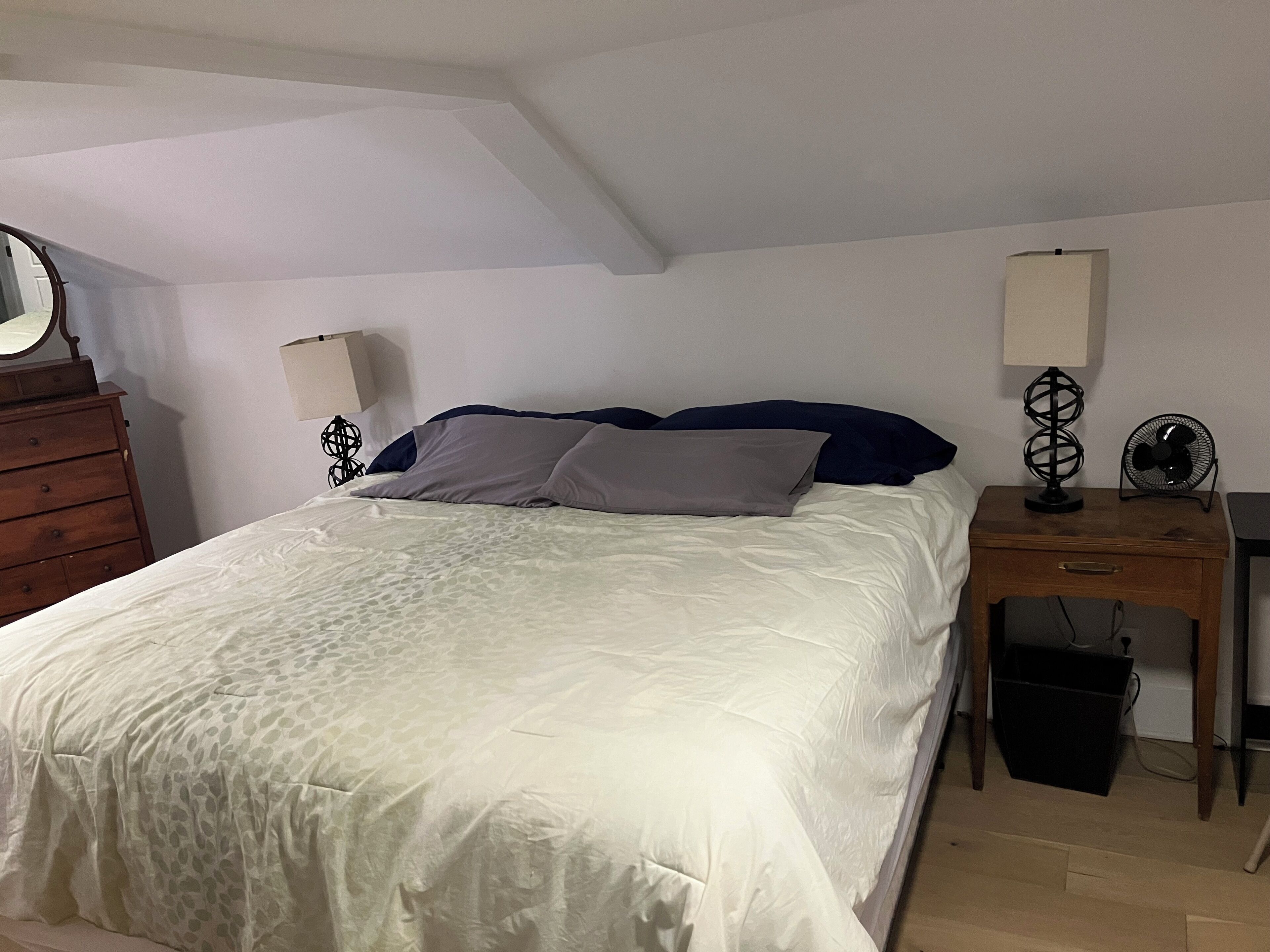 Ein Schlafzimmer mit einem Bett, zwei Nachttischen, einem Schminktisch und einem Spiegel.