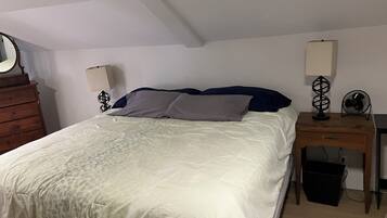 Un dormitorio con cama, dos mesitas de noche, cómoda y espejo.