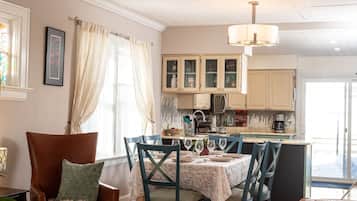 Un salon chaleureux avec un coin repas, un parquet et un lustre.