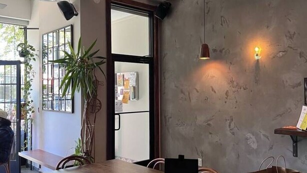 A modern dining area with a long wooden table, chairs, and a potted plant. - 20 Min to Times Square-Stylish 2 BR w/Parking (West New York)