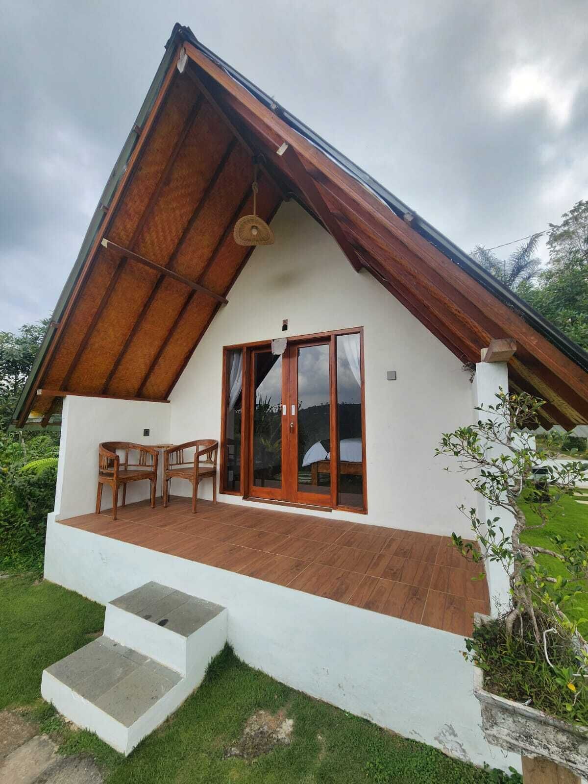 A two-story house with a wooden deck, a set of stairs leading to the entrance, and a large sliding glass door.