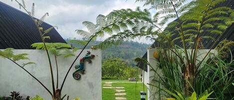 Un sendero conduce a una casa con vistas a un exuberante jardín y colinas distantes.