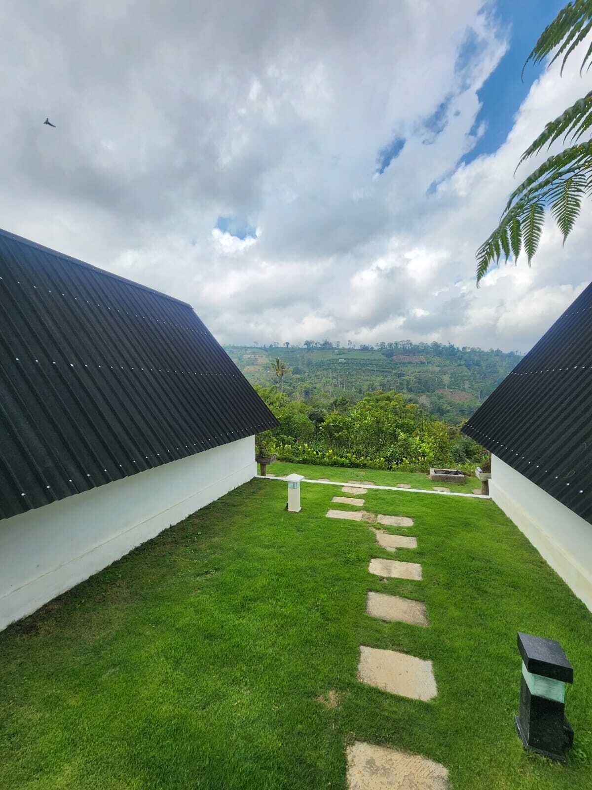 Ein Innenhof mit freiem Blick auf eine hügelige Landschaft, umgeben von Gebäuden mit dunklen Dächern und weißen Wänden.