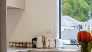 Eine moderne Küche mit Holzausstattung, einem runden Esstisch und einem Fenster mit Blick auf Bäume und Gebäude.