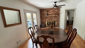 A dining room with a round table, wooden chairs, a ceiling fan, and a brick fireplace. - 4 BR/3 BA-Great for extended stays- Close to Savannah River Site & Masters Golf (Aiken)