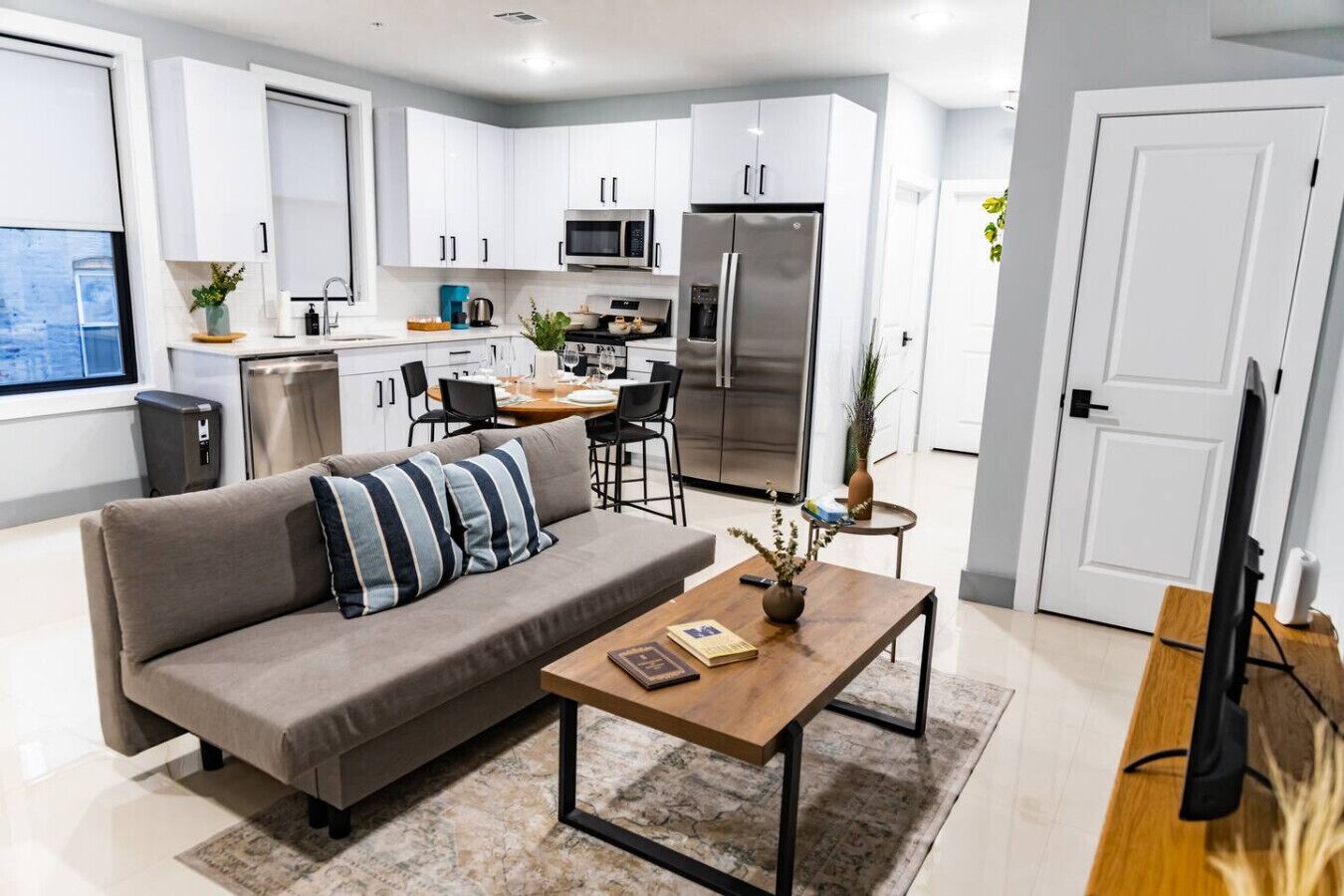 A modern apartment with a living room, kitchenette, and dining area.