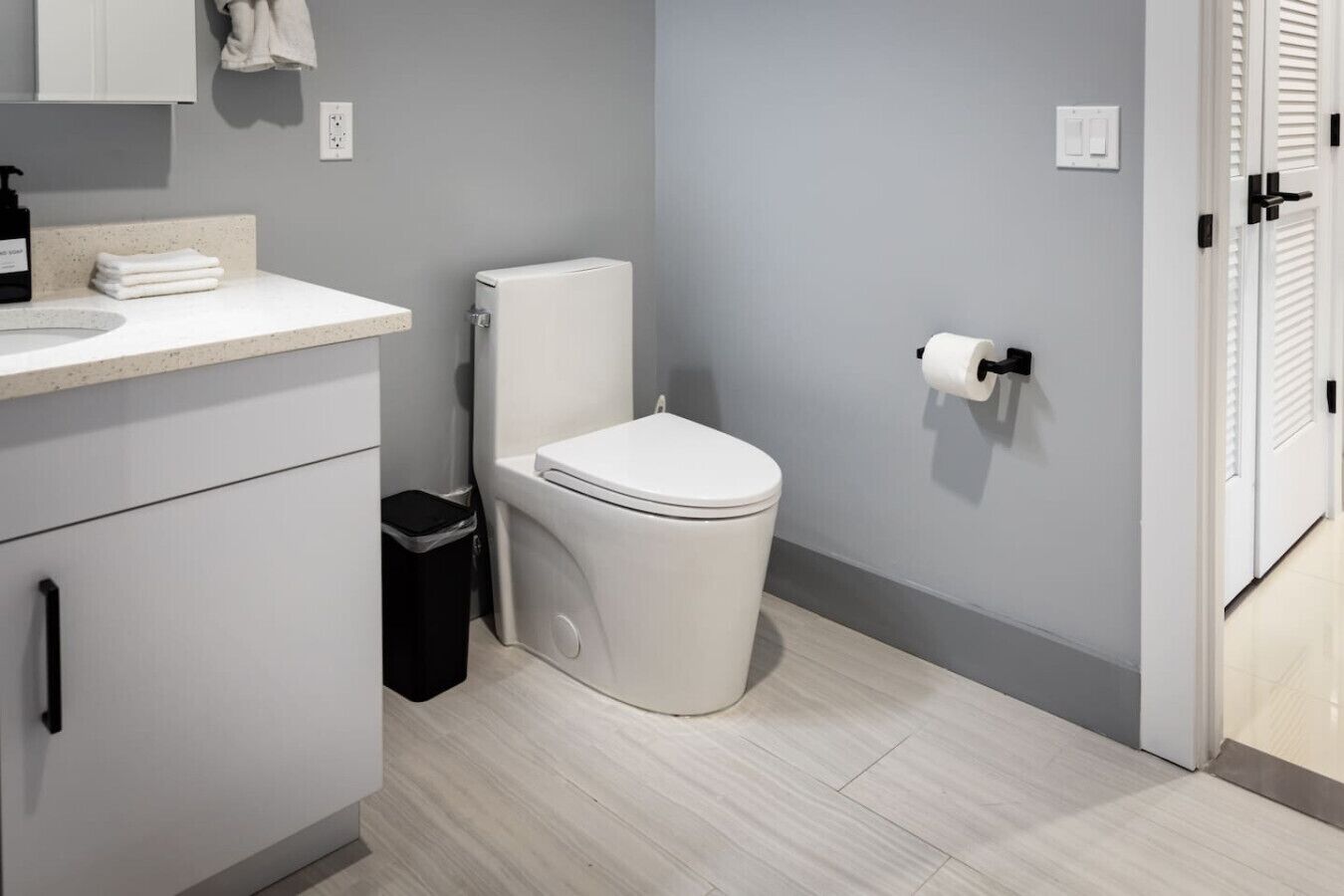A modern bathroom with a toilet, sink, and a trash bin.