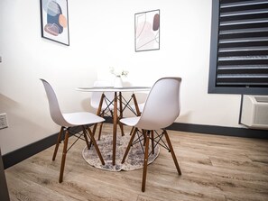 A dining area with a round table and four chairs, a vase with flowers, and two framed artworks on the wall. - Prime Location-Free Parking-20 Min to Times Square (West New York)