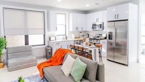 Una cocina moderna con armarios blancos, un refrigerador de acero inoxidable y un microondas.