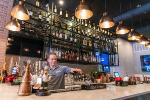Un bar avec des étagères remplies de bouteilles, un barman et des décorations de Noël.