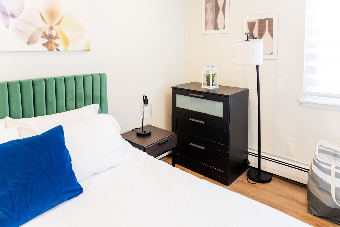 Habitación de hotel con cama, mesita de noche, lámpara, cómoda y ventana.