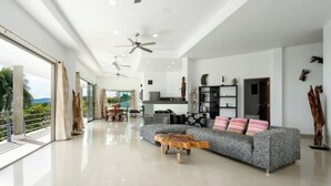 A spacious living room with a grey sofa, wooden coffee table, and ceiling fans.