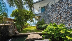A modern building with a stone wall, a small water feature, and lush greenery.