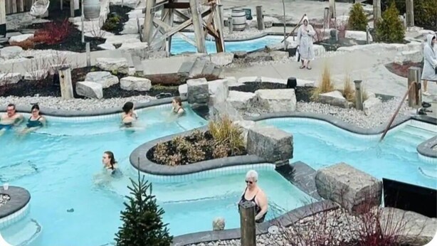 Un lodge rústico con piscina, cabañas de madera y un paisaje natural.