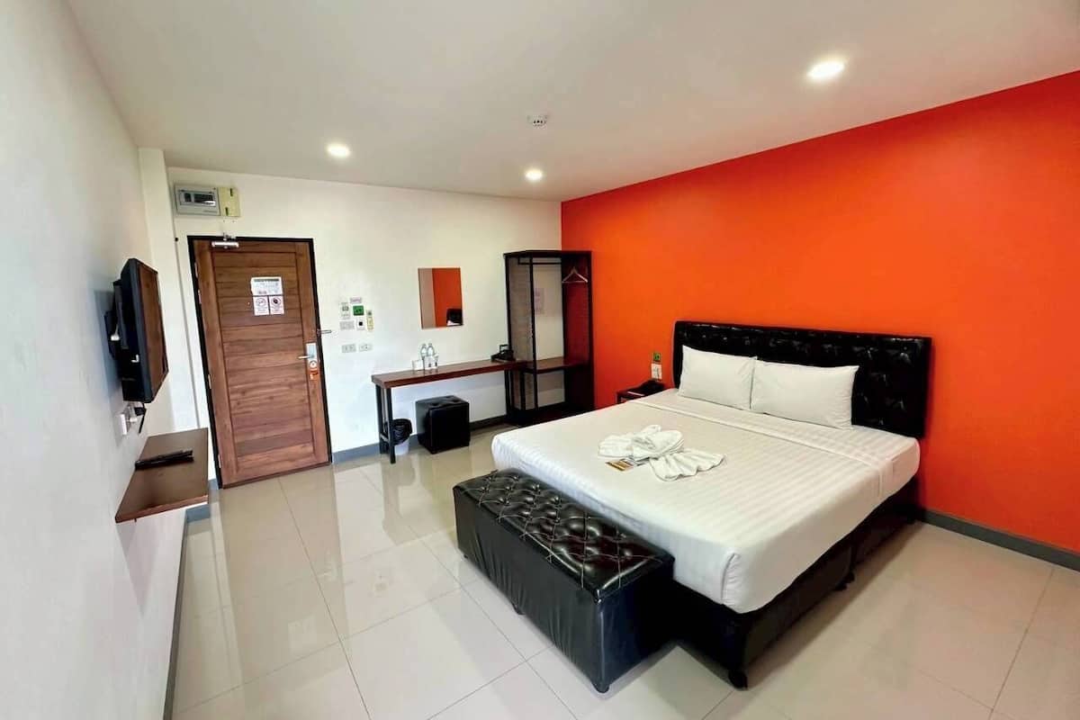 A modern hotel room with a large bed, a wooden desk, a television, and a bathroom.