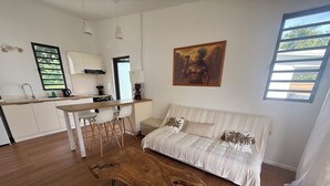Un salon moderne avec une table basse en bois, un canapé agrémenté de coussins à motifs et un tableau accroché au mur.