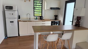 Une cuisine compacte équipée d’un four à micro-ondes, d’un réfrigérateur, d’un évier et d’une table à manger en bois avec des chaises.