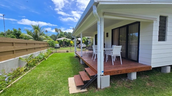 A house with a covered porch, a small outdoor seating area, and a well-maintained lawn.