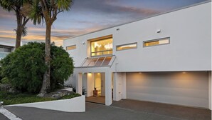 Et moderne hus i to etager med garage, store vinduer og en velholdt have.
