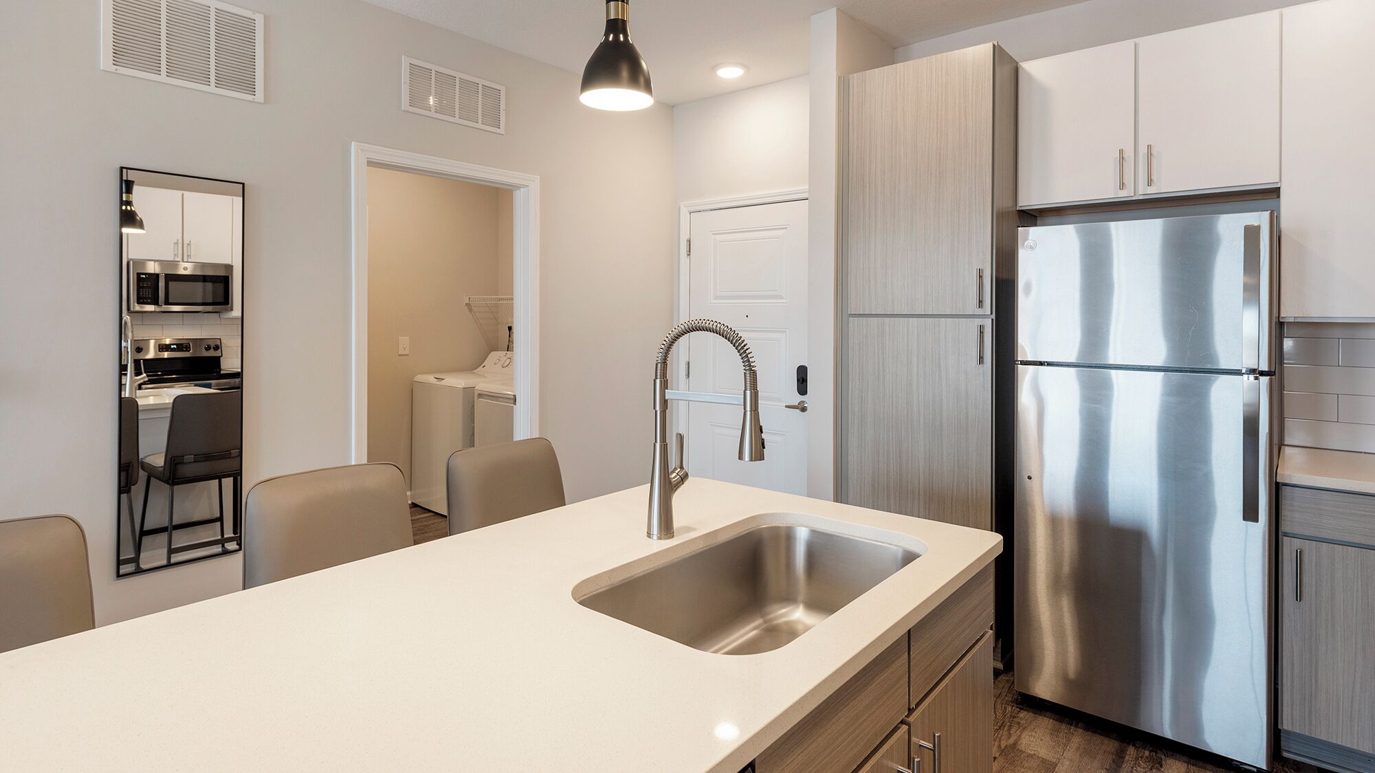 A modern kitchen with a stainless steel refrigerator, a built-in microwave, and a sink with a contemporary faucet.