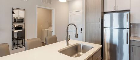 A modern kitchen with a stainless steel refrigerator, a built-in microwave, and a sink with a contemporary faucet.