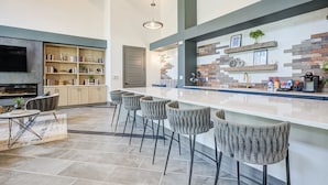 A modern kitchen with a long island, bar stools, and a built-in TV. - Landing Near UNC Charlotte (Charlotte)