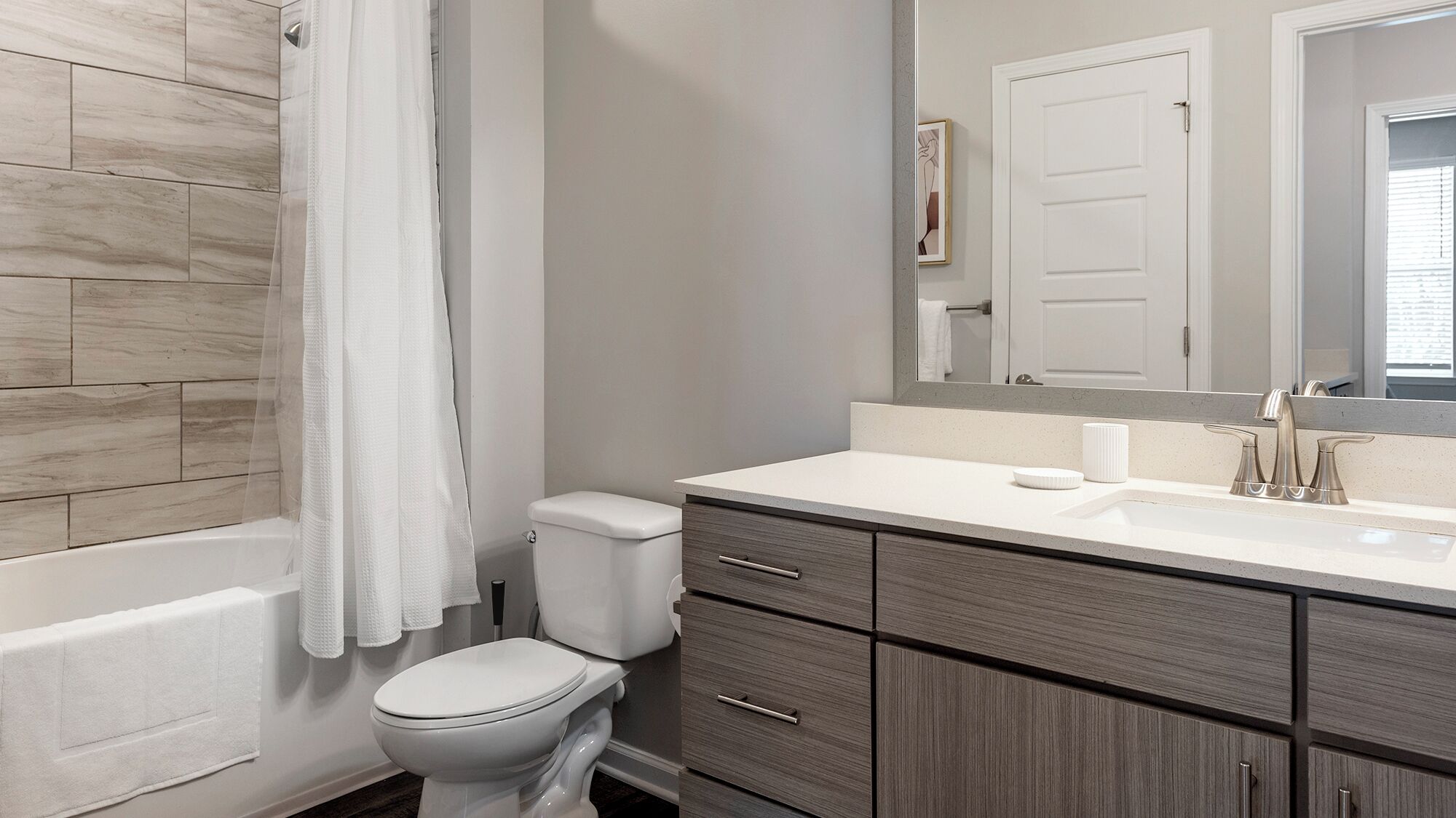 Un bagno moderno con vasca, servizi igienici e mobile lavabo con specchio.