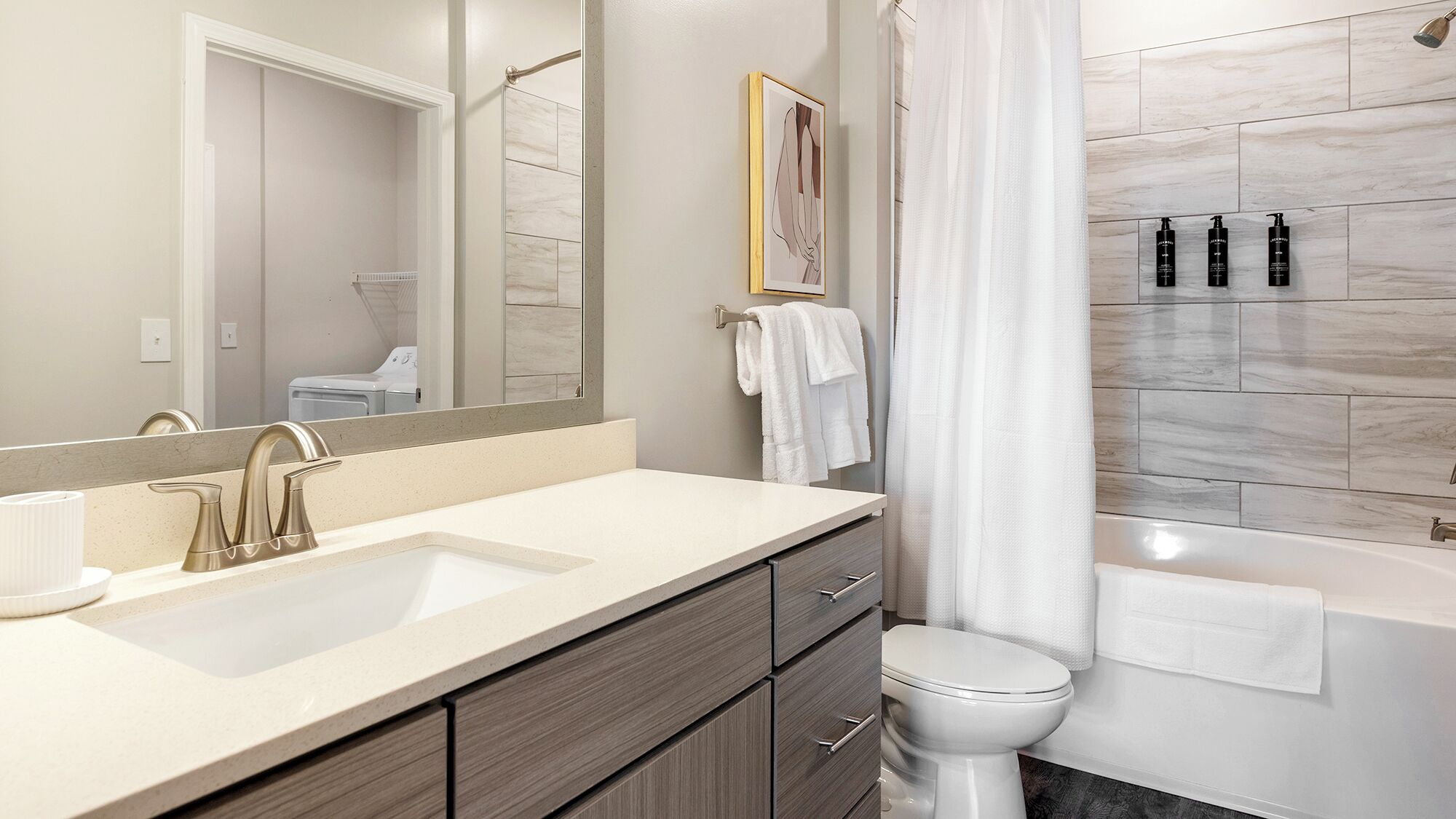 Un baño moderno con un espejo grande, dos lavamanos, un inodoro y una bañera.