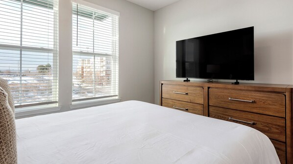 A bedroom with a large bed, a wooden dresser, and a flat-screen TV. - Landing Near UNC Charlotte (Charlotte)