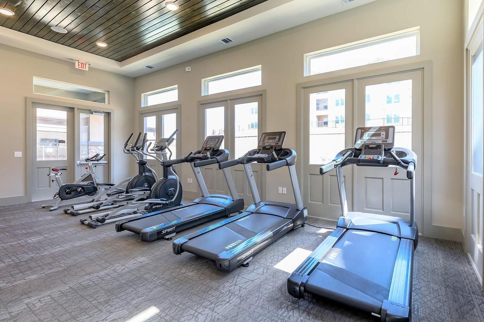 Une salle de sport équipée de plusieurs tapis de course, de plusieurs appareils elliptiques et d’un vélo d’appartement.