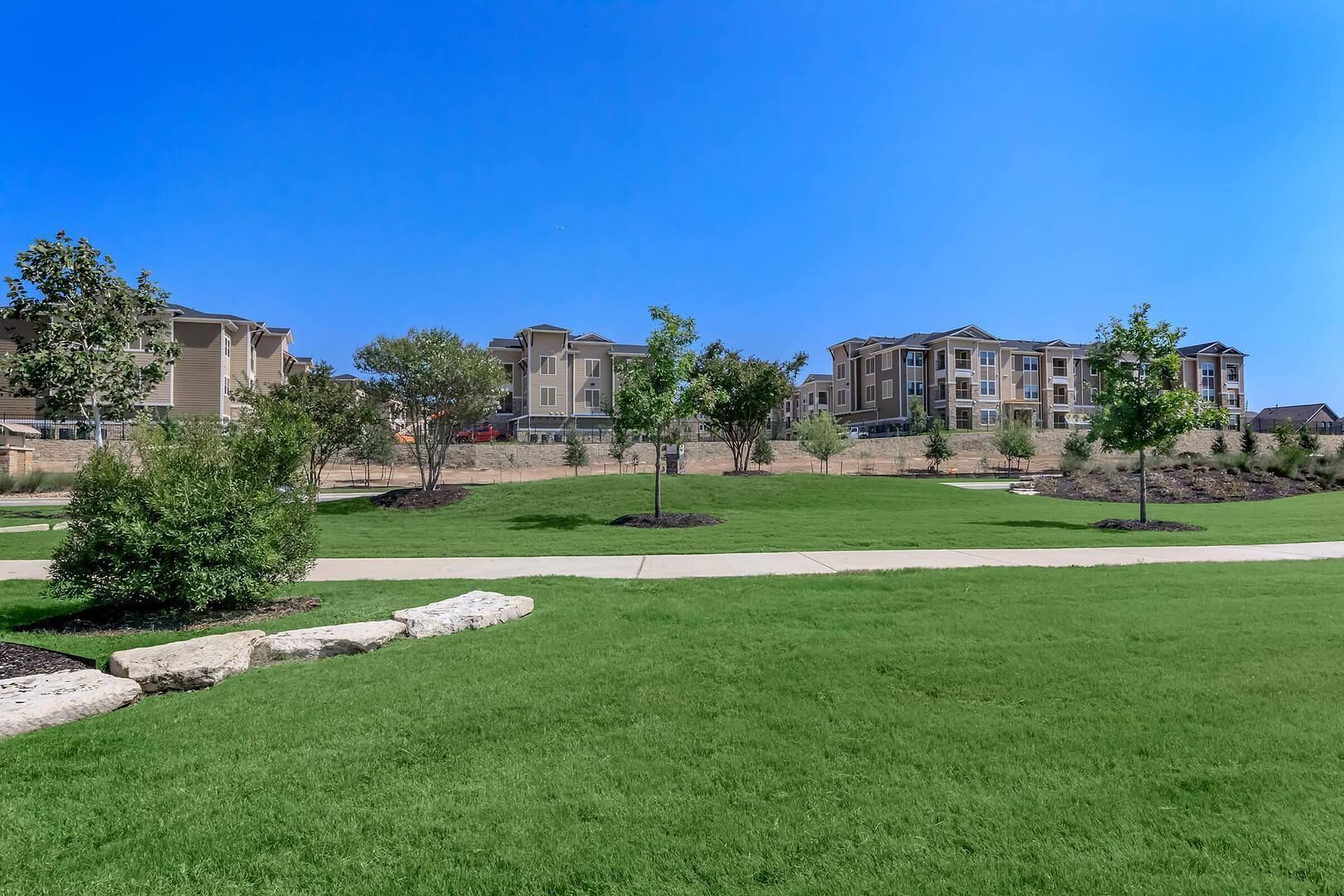 A residential area with modern apartment buildings, well-maintained lawns, and a clear sky.