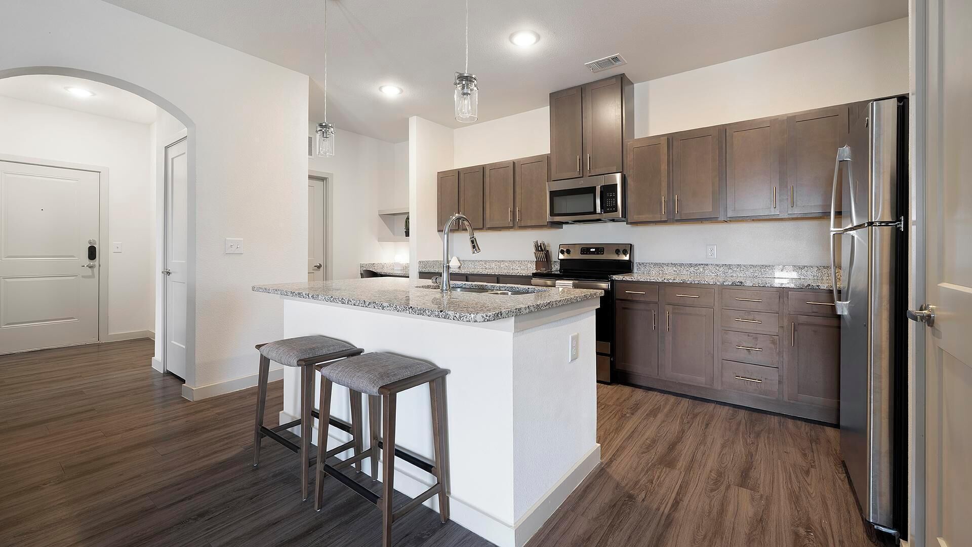 A modern kitchen with a central island, stainless steel appliances, and wooden cabinetry.