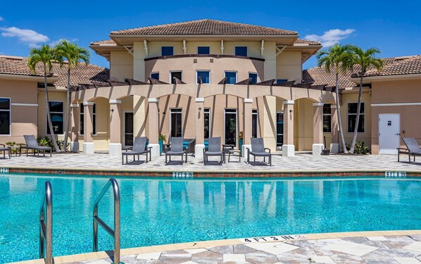 A poolside area with lounge chairs and a clear blue pool.