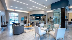 A modern hotel lobby with a curved seating area, a glass coffee table, and a kitchen visible through the glass partition. - Landing Apartments - North Charlotte (Charlotte)