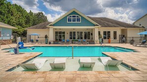 A pool area with a clear view of the pool, lounge chairs, and a building with a blue roof. - Landing Apartments - North Charlotte (Charlotte)
