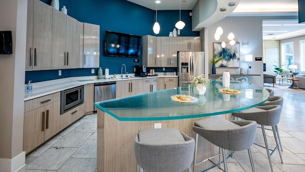 A modern kitchen with a central island, stainless steel appliances, and a blue accent wall. - Landing Apartments - North Charlotte (Charlotte)
