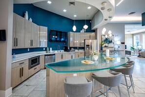 Una cocina moderna con una isla central, electrodomésticos de acero inoxidable y una pared de acento azul.